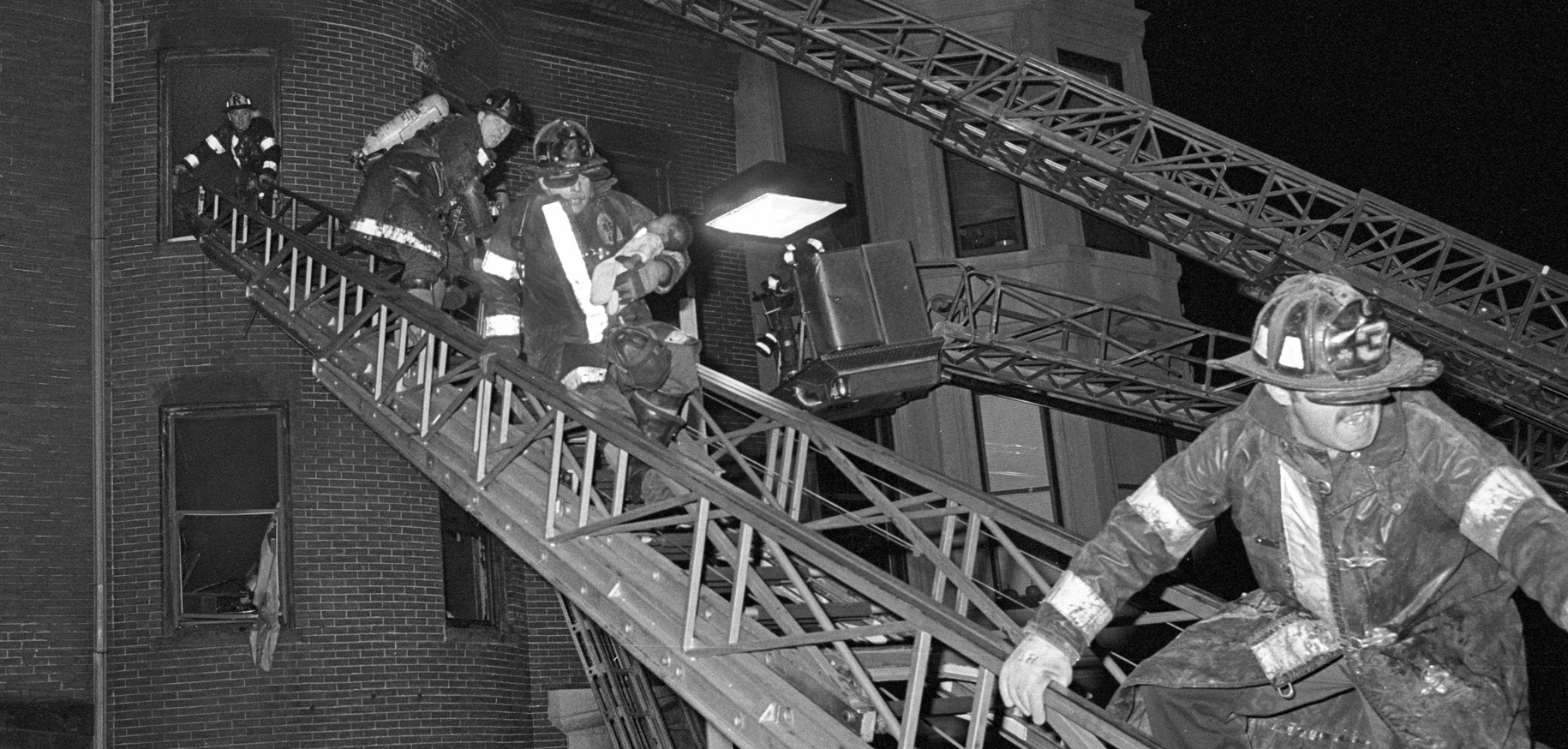 Firefighters on a ladder at night with text 'Get It While It's Hot'.