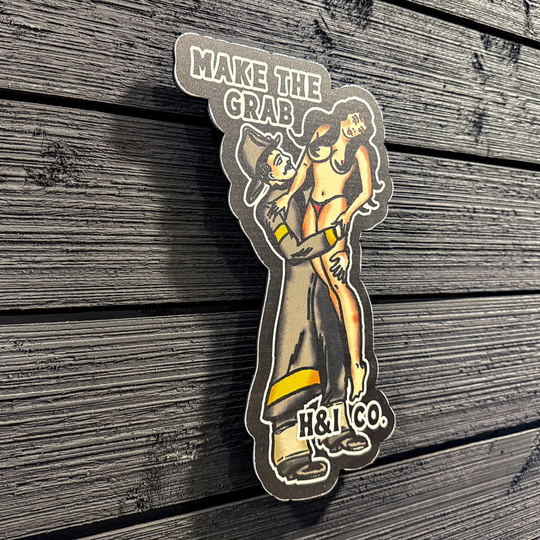 Metal sign with a design of a person holding a crab and text 'MAKE THE CRAB H&I CO.' on a wooden surface.